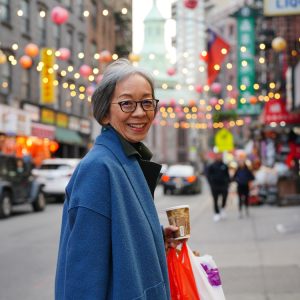 Author Grace Young holding a coffee cup and carrying shopping bags